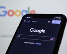 Smartphone mit Google-Suchseite vor einem Bildschirm mit Google-Logo