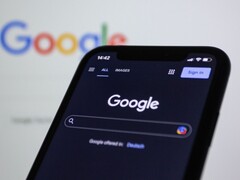 Smartphone mit Google-Suchseite vor einem Bildschirm mit Google-Logo