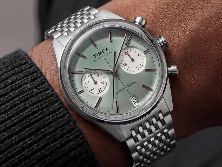 Timex Marlin Jet Chronograph mit salbeigrünem Zifferblatt und Edelstahlarmband am Handgelenk, wobei das gewölbte Uhrenglas und die abgerundete retrofuturistische Gehäuseform zu sehen sind.