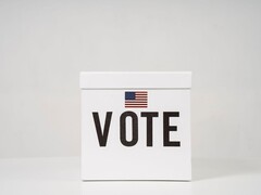 Weiße Wahlurne mit der Aufschrift Vote und einer kleinen US-Flagge