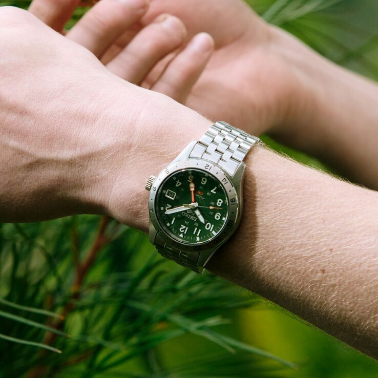Vorderansicht der Seiko 5 Sports Field GMT HDB001 mit grünem Zifferblatt, feststehender 24-Stunden-Lünette aus Edelstahl, orangefarbenem GMT-Zeiger und einem fünfgliedrigen Edelstahlarmband.
