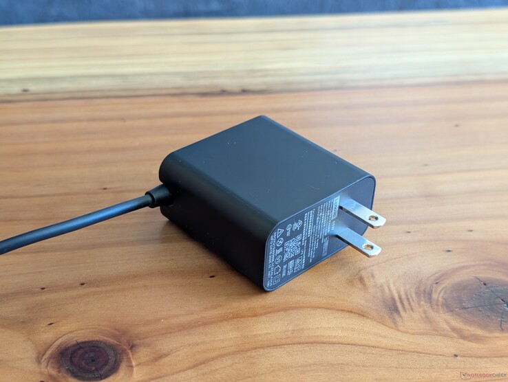 USB-C-Netzteil mit 65 Watt, das dem Lenovo Yoga Slim 7 14 beiliegt. Auffällig sind die nicht einziehbaren Netzsteckerstifte und das integrierte USB-C-Kabel am anderen Ende