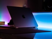 Halb geöffnetes MacBook in einem dunklen Raum, aus dem Spalt fällt Licht auf den Tisch