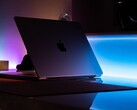 Halb geöffnetes MacBook in einem dunklen Raum, aus dem Spalt fällt Licht auf den Tisch