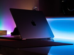 Halb geöffnetes MacBook in einem dunklen Raum, aus dem Spalt fällt Licht auf den Tisch