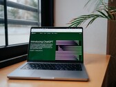 Laptop auf einem Schreibtisch am Fenster, auf dem Bildschirm ist die ChatGPT-Webseite von OpenAI geöffnet