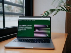 Laptop auf einem Schreibtisch am Fenster, auf dem Bildschirm ist die ChatGPT-Webseite von OpenAI geöffnet