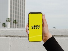 Hand hält ein Smartphone, auf dessen gelbem Bildschirm groß eSIM steht.