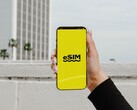 Hand hält ein Smartphone, auf dessen gelbem Bildschirm groß eSIM steht.