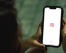 Frau hält ein Smartphone in beiden Händen, auf dem Display erscheint der Startbildschirm von Instagram