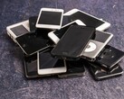 Haufen ausgemusterter Smartphones auf grauem Untergrund