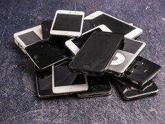 Haufen ausgemusterter Smartphones auf grauem Untergrund