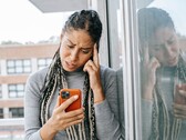 Frau schaut mit ernstem Gesichtsausdruck auf ihr Smartphone