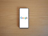 Smartphone mit Google-Startbildschirm auf einem Holztisch