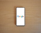 Smartphone mit Google-Startbildschirm auf einem Holztisch